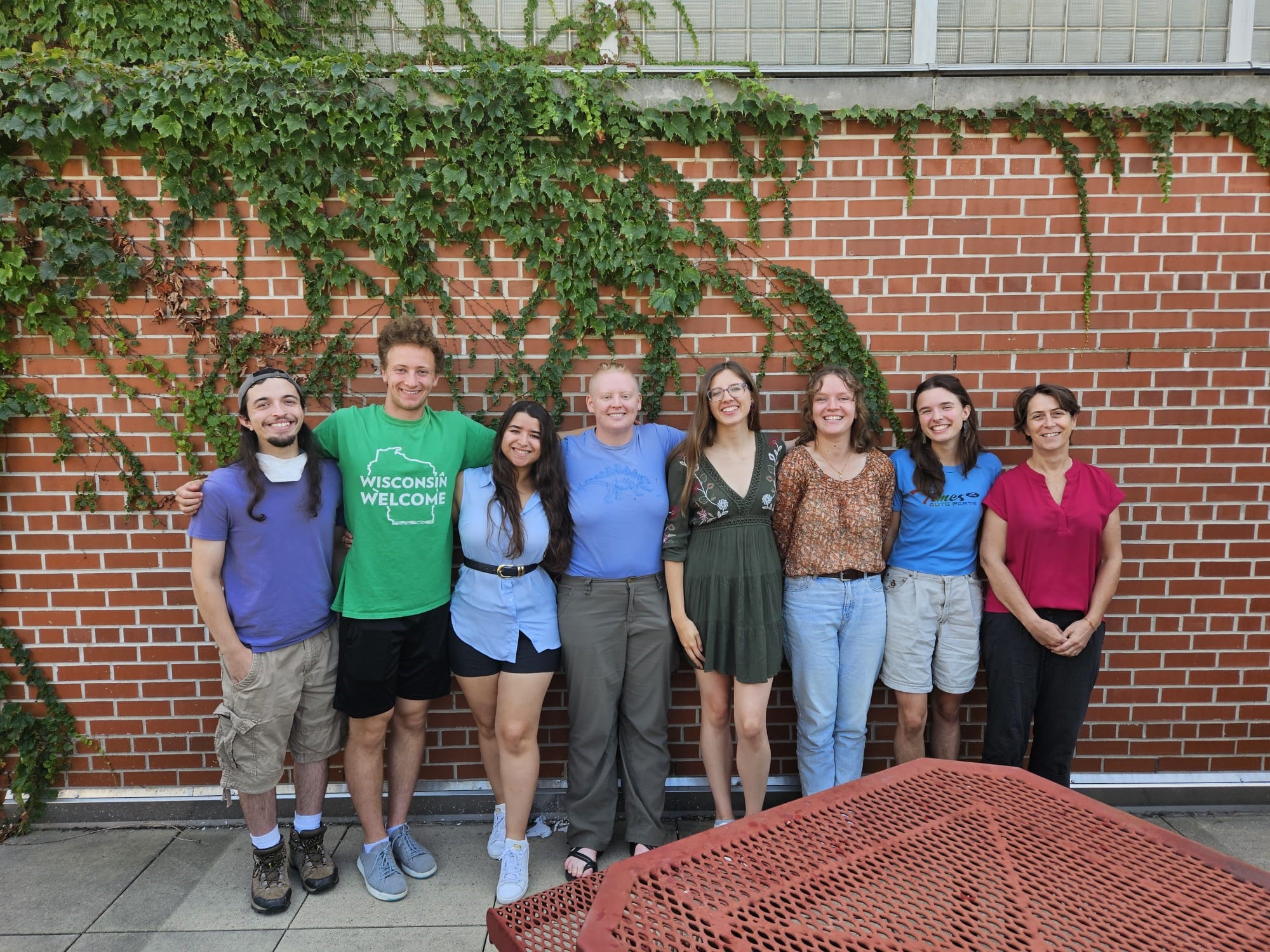 Eight people stand next to each other smiling at the camera